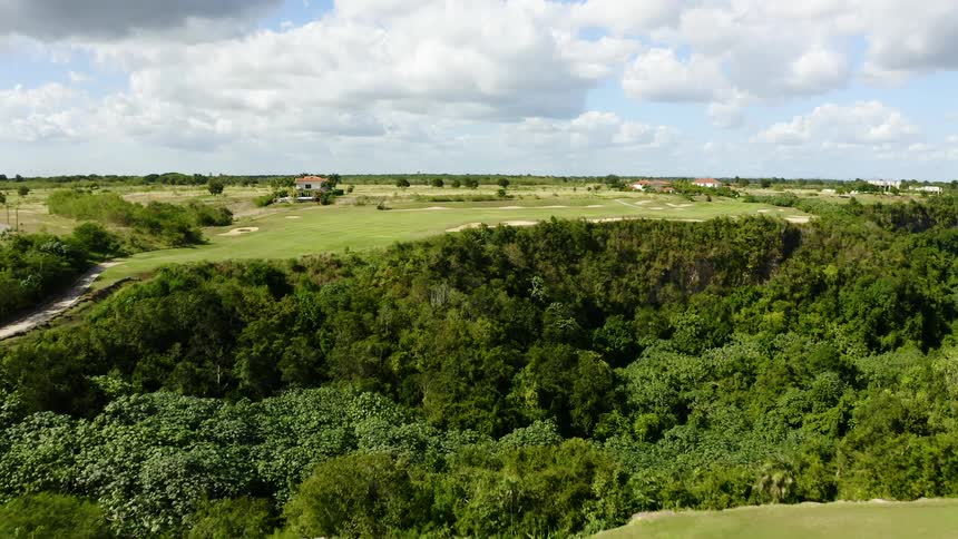 A golf course atop a canyon filled with forest on a sunny day