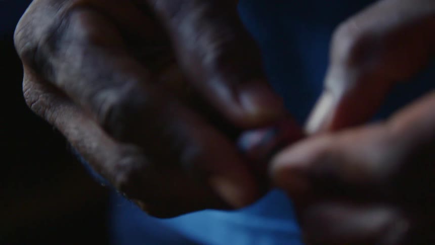 A man peeling a fruit with his nails