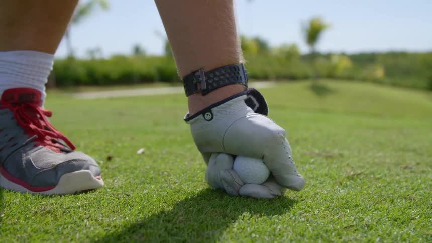 A golfer teeing up on a golf course