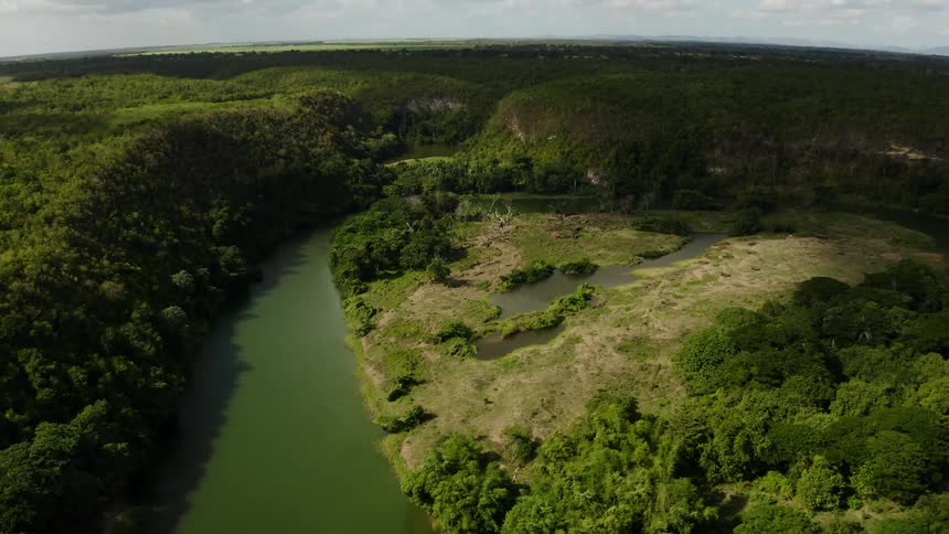 A large river carves its way through a dense green forested landscape