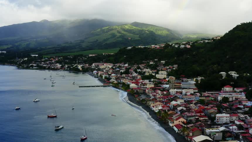 Aerial shot of a coastal town with foggy mountains
