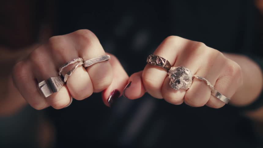 Woman makes fists with her hands to show all the rings on her fingers