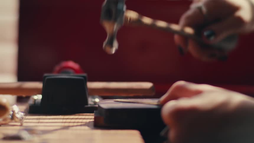 A woman using a small hammer inside