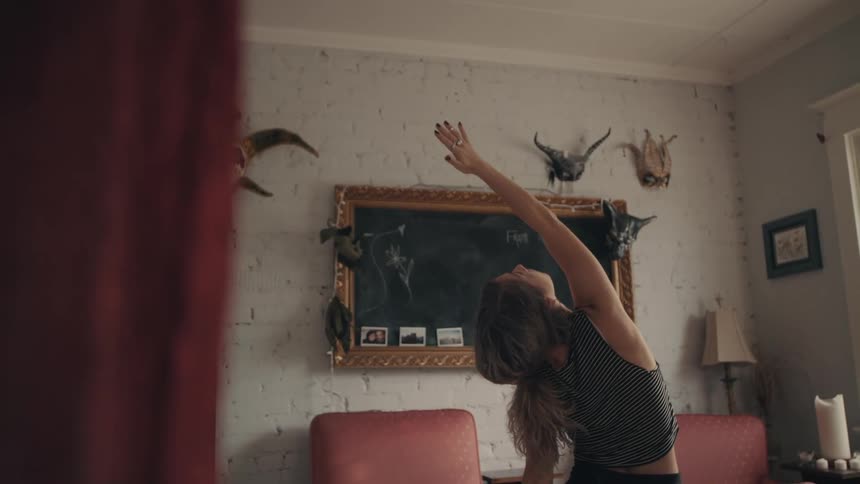 Woman stretches into a yoga pose in room near chairs