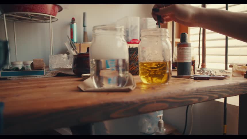 A woman stirs a bottle of dark yellow colored liquid