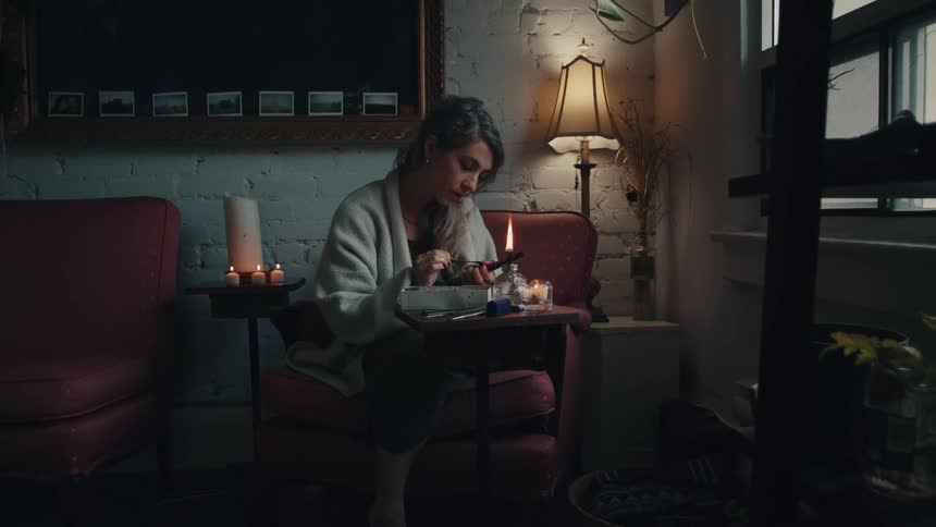 A woman sitting at home heats a tool in an open flame