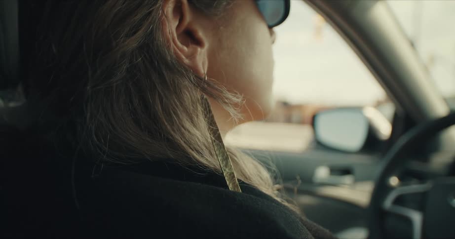 Woman with glasses and earring sits in a car