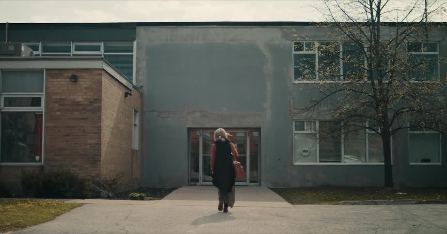 Woman in a black dress enters a building in autumn