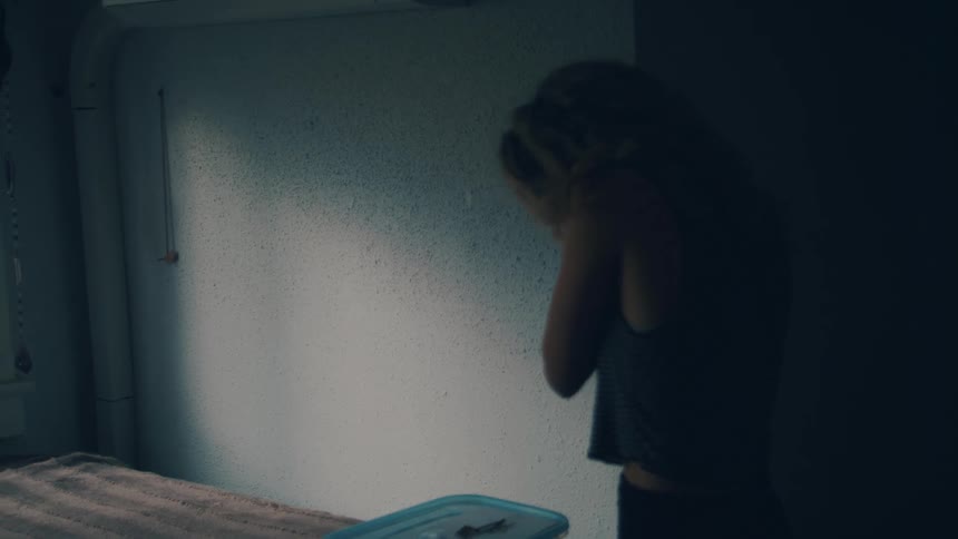 Blonde woman with curly hair puts on earrings in her room