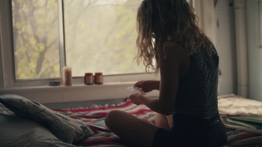 A woman sitting on a bed with a blanket and pillows