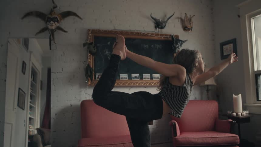 A woman practices yoga while in the living room of her apartment