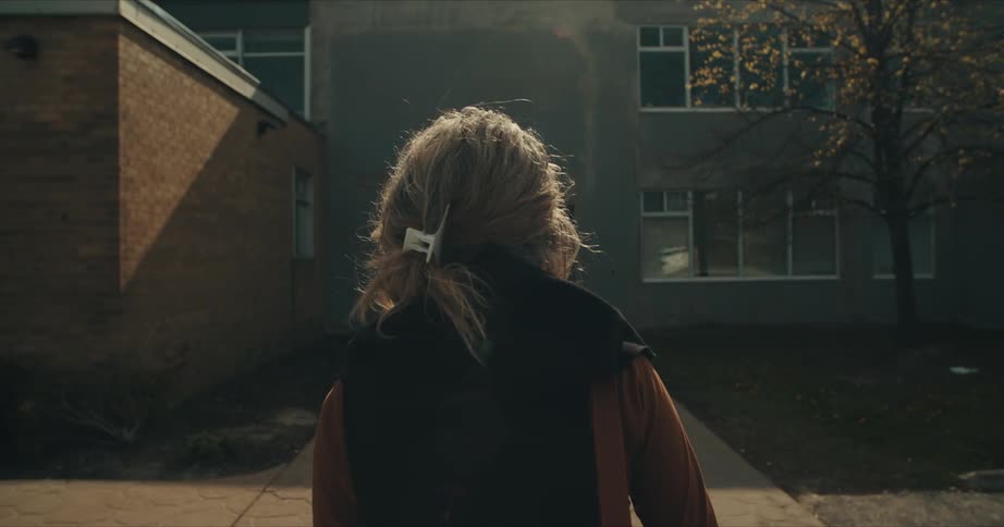 A woman with a handbag walking towards a building with windows