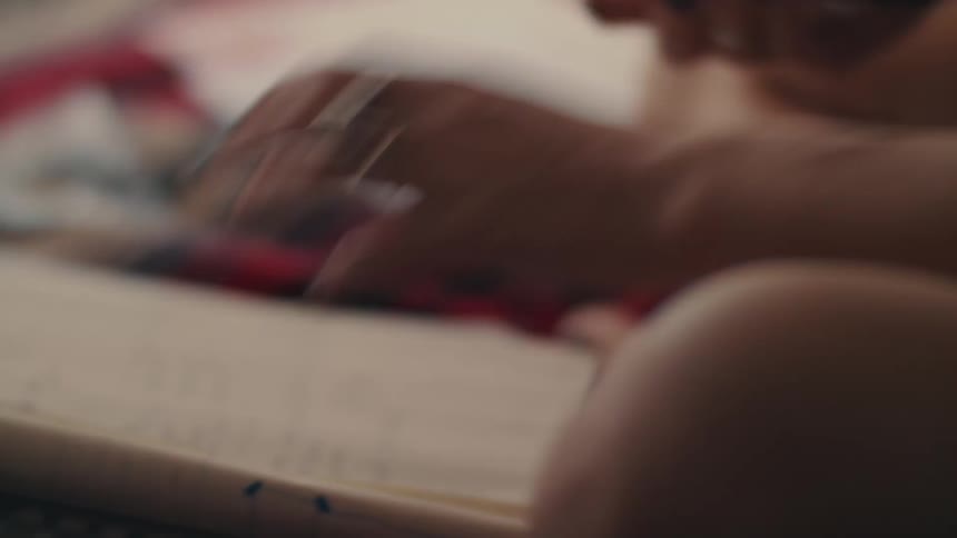 Woman sitting in bed organizes her notebooks and markers