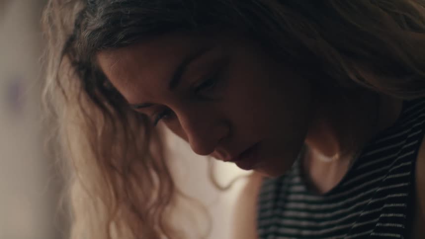A young woman inside looks down and contemplates