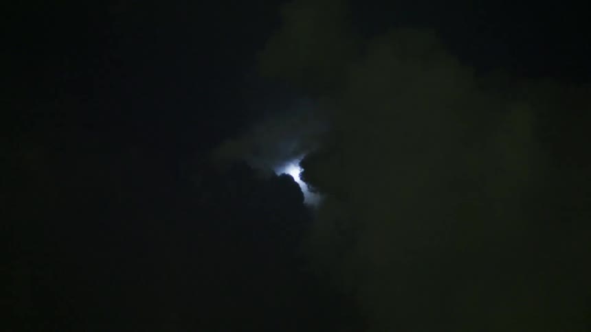 The sky with clouds lightning and the moon