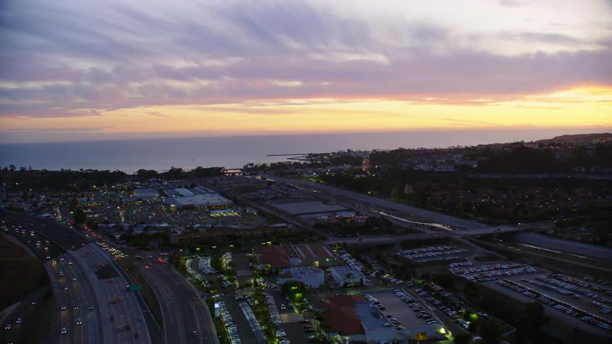 Cars travel on highways and city streets at sunset in a city near the ocean shore
