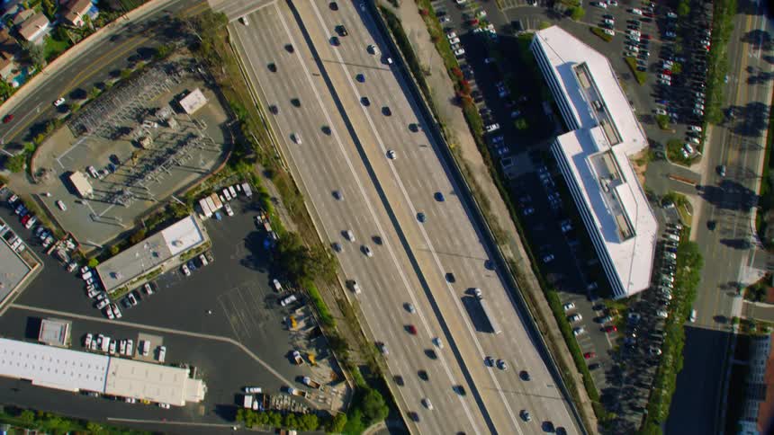 Traffic moves smoothly down a highway surrounded by suburban houses and businesses