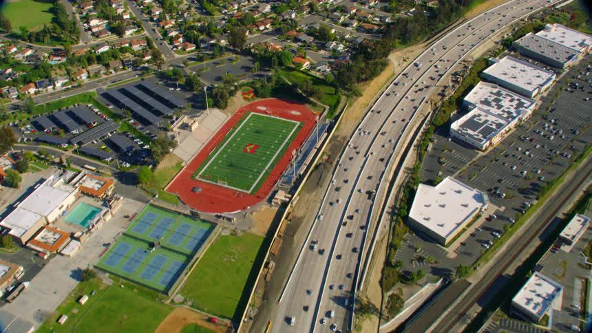 Traffic follows freeway past athletic fields and neighborhoods