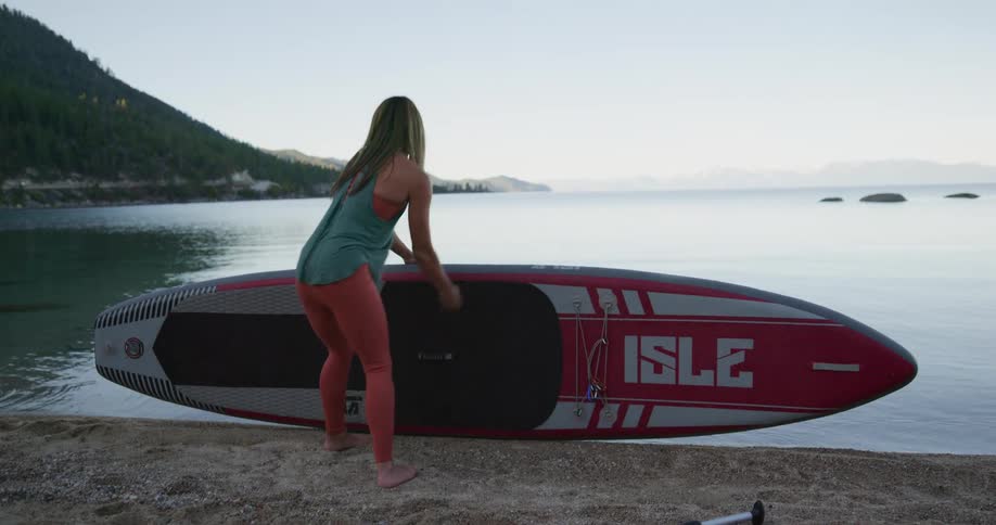A female caucasian putting a boat into a river