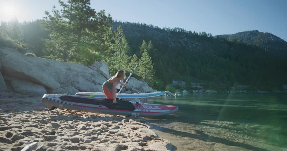 Two women putting their paddle boards in to the water