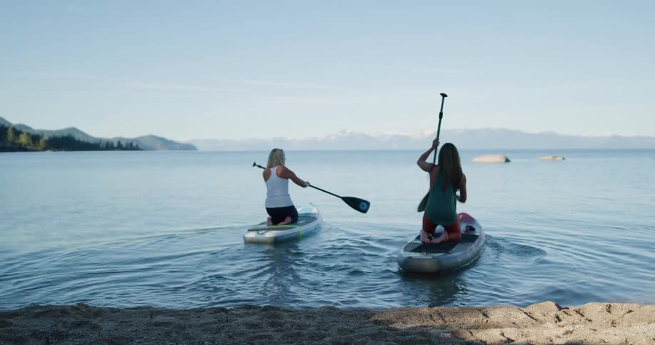 Two women get into canoes and paddle off
