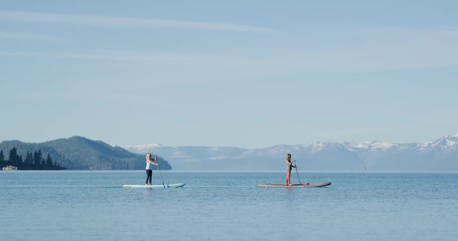 Two women paddle boarding in a lake