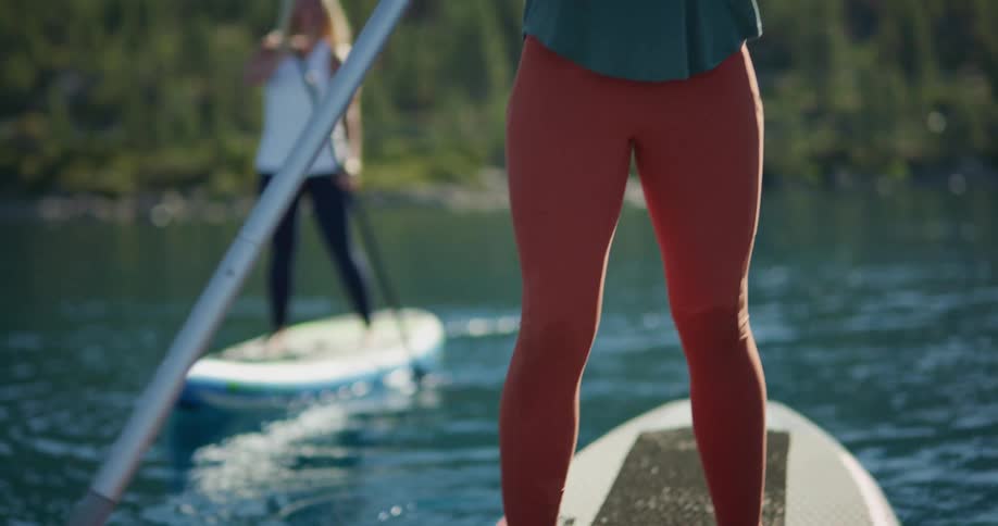 Two women paddle boarding on a lake