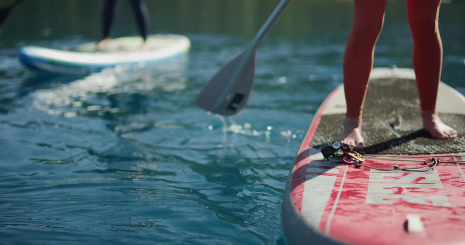 Two women paddle boarding on a lake on a summer day