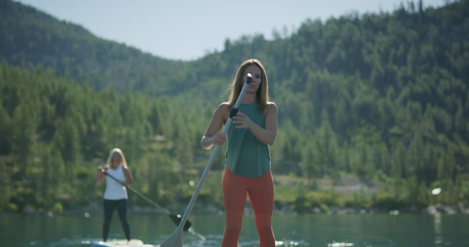 Two women paddle boarding on a lake