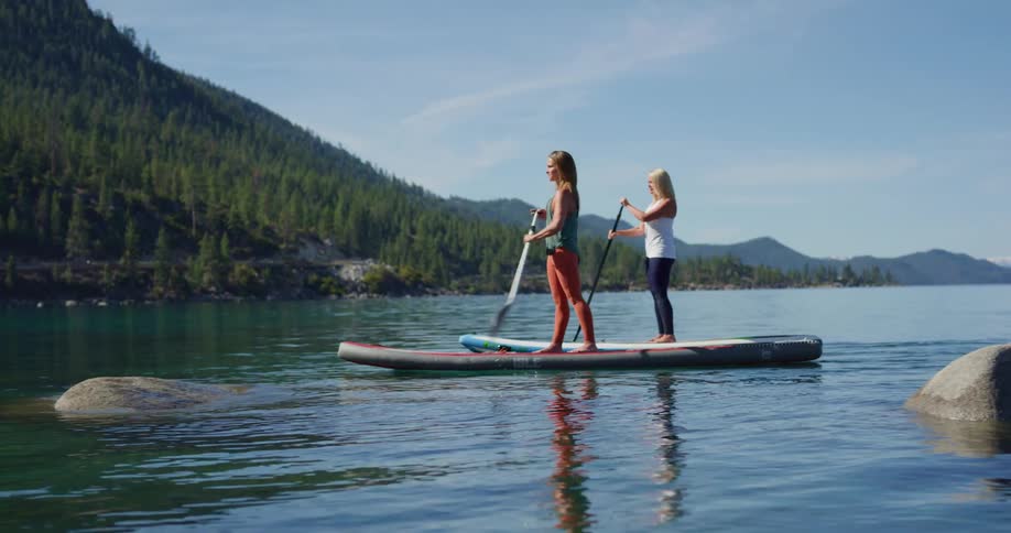 Two woman paddle boarding on a river