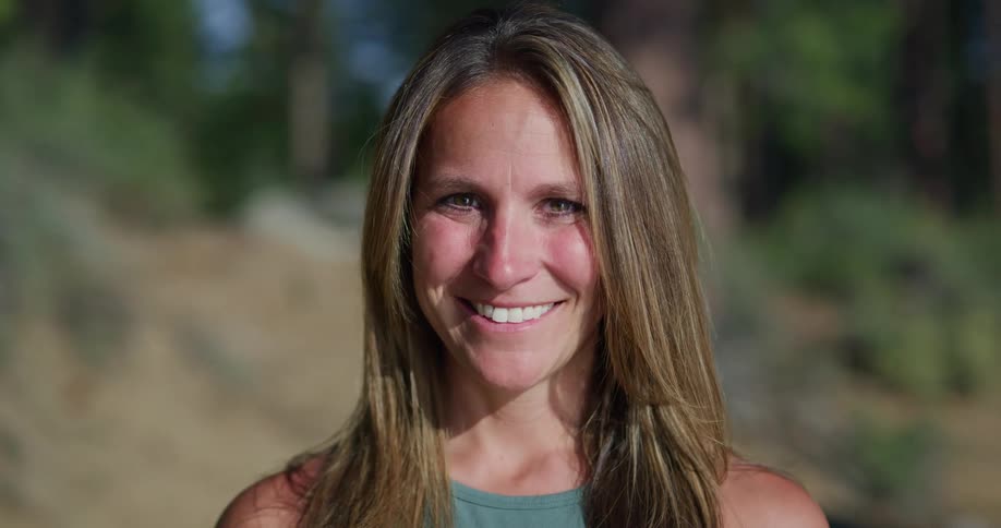 A woman is smiling outdoors during midday