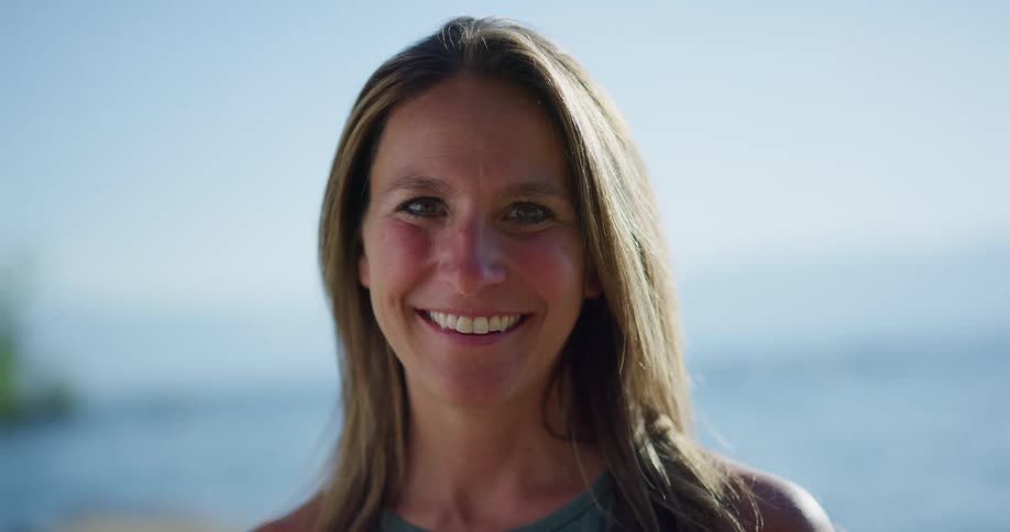 A woman is smiling at the beach during midday