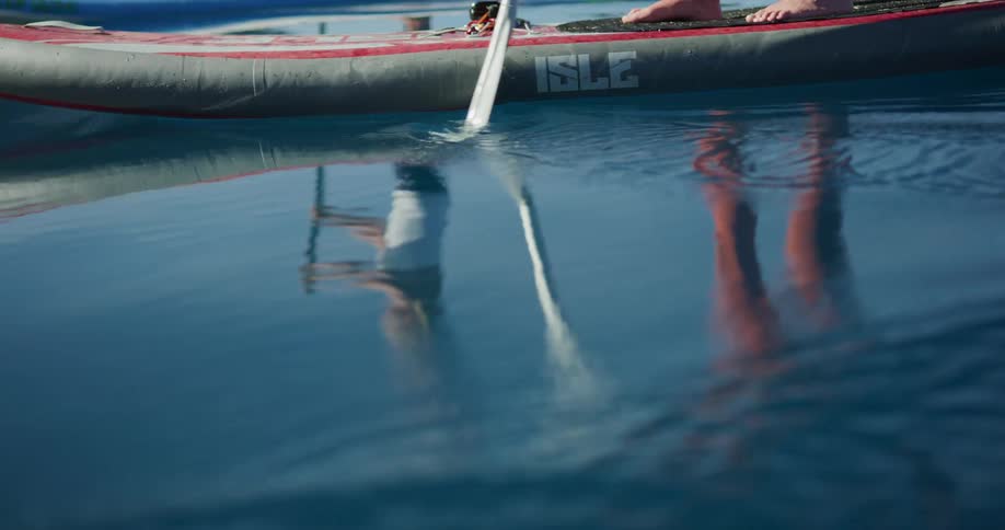 Two women standing on paddle boards paddle through a tranquil lake