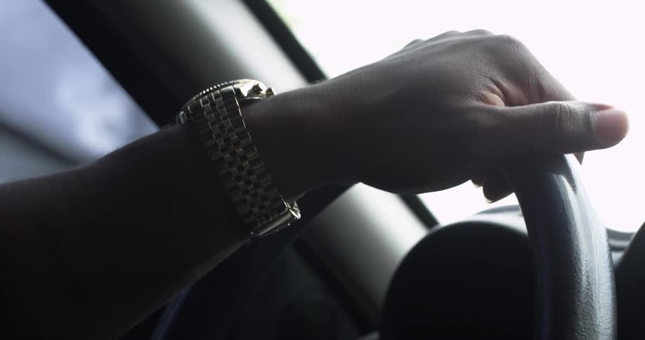 Close up of a hand steering a wheel of a moving car