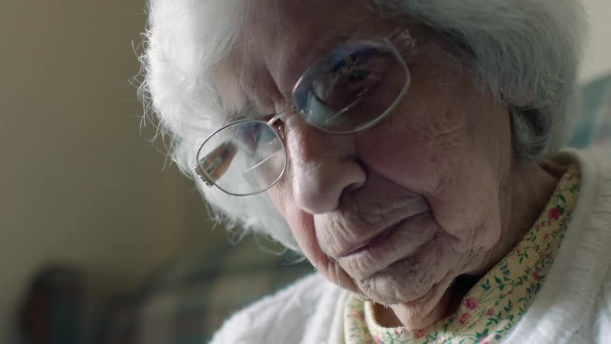 An elderly woman looks down intently