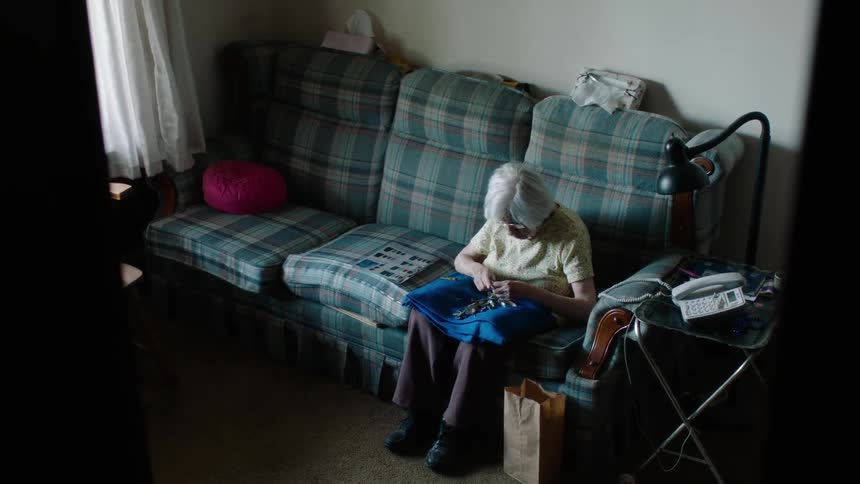A woman is sitting on a couch knitting