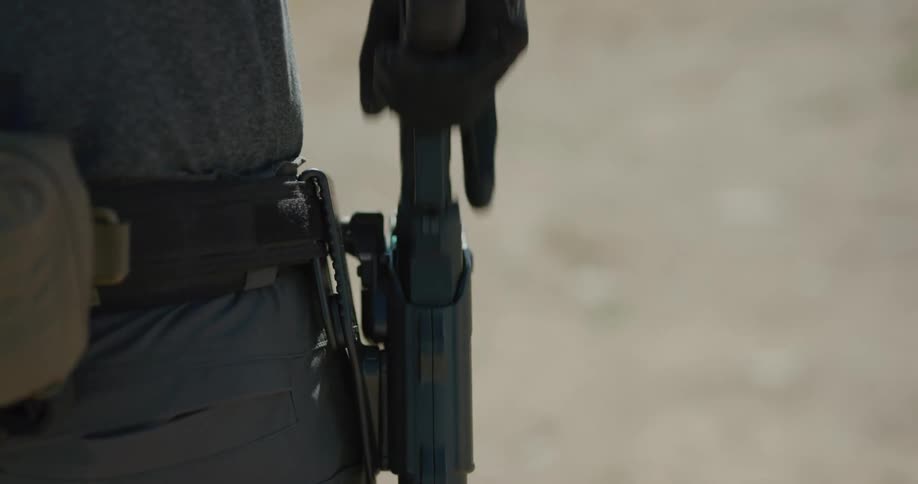 A man draws his pistol from his side holster