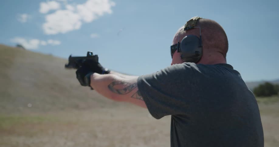 A man shooting a gun at a target on a hill
