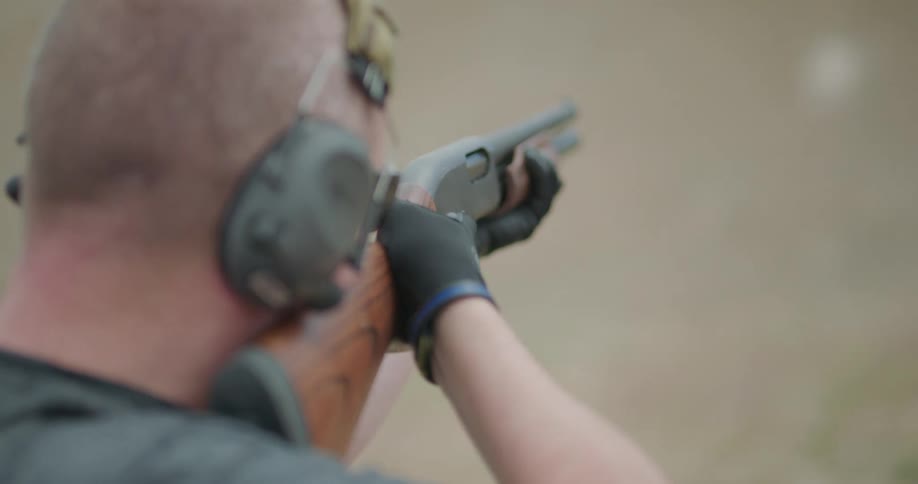 A man shoulders his shotgun and shoots at a target