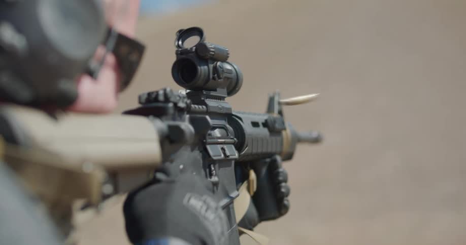 A man is firing a scoped automatic rifle
