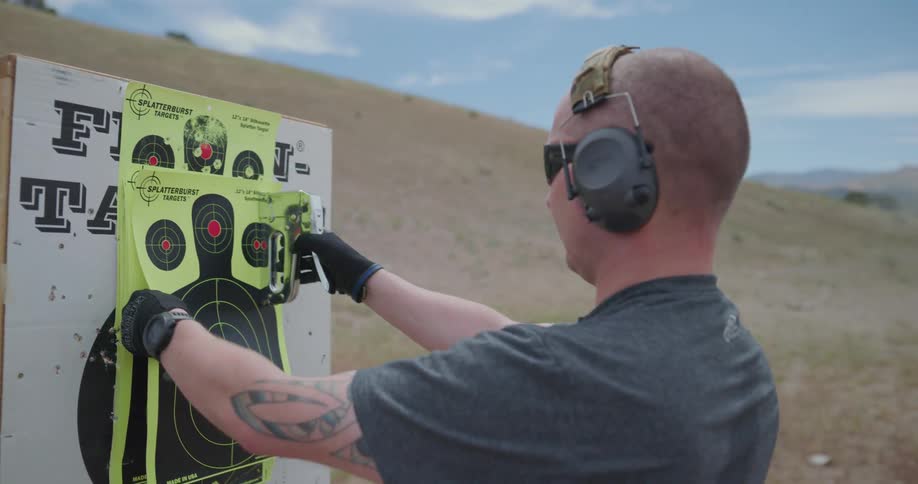 A man carries a paper target and staples it to an easel for target practice