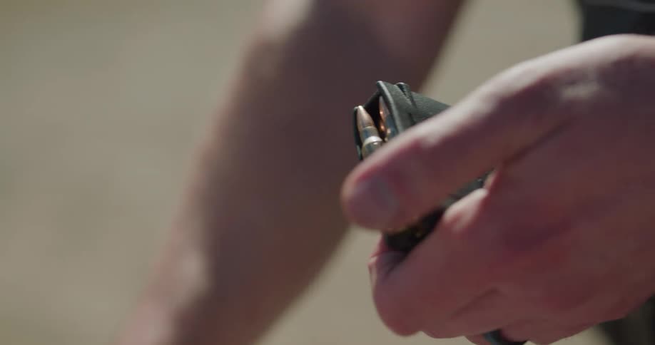 A person putting bullets in a gun