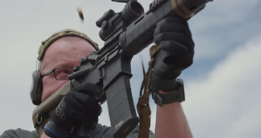 A man looks through the scope of a rifle and fires several times before checking his target