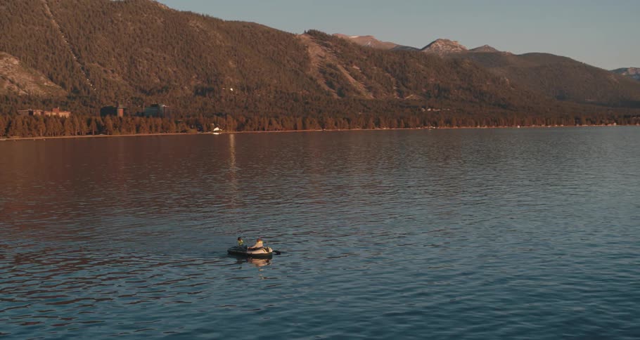 An aerial view of two people in a rowboat on a lake