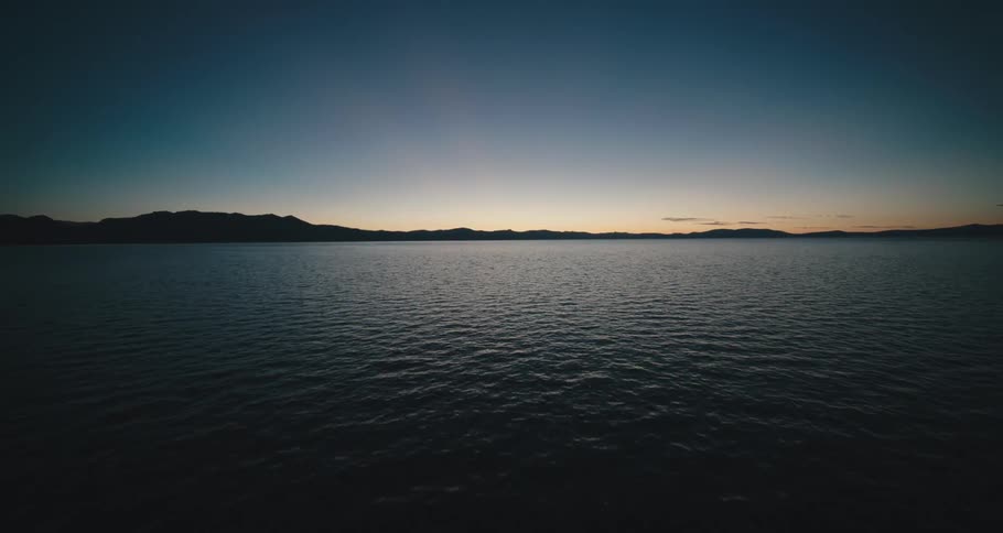 An aerial view of an ocean is displayed at dusk