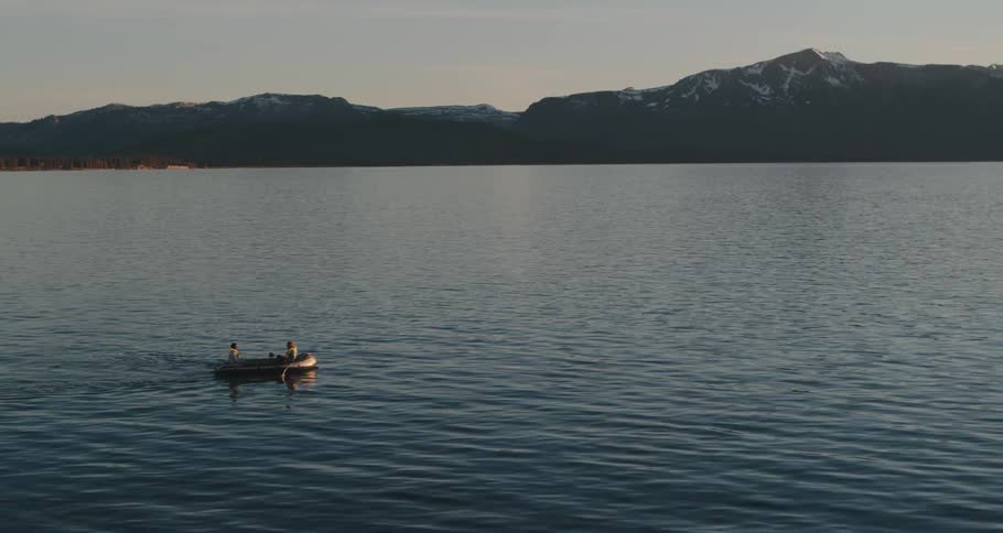 Two people in a rowboat on a lake with mountains in the distance