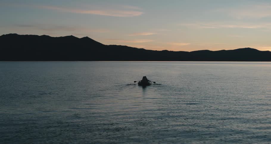 An aerial view of a row boat on a lake at dusk