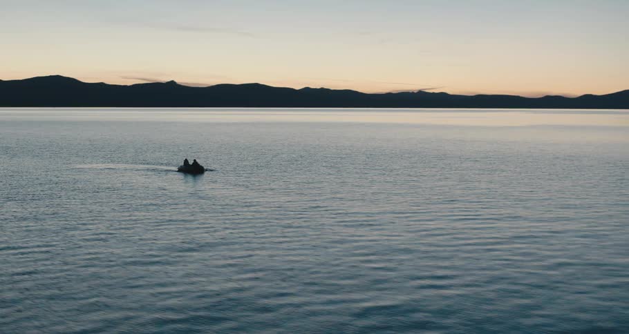 An aerial view of people in a rowboat on a lake at dusk