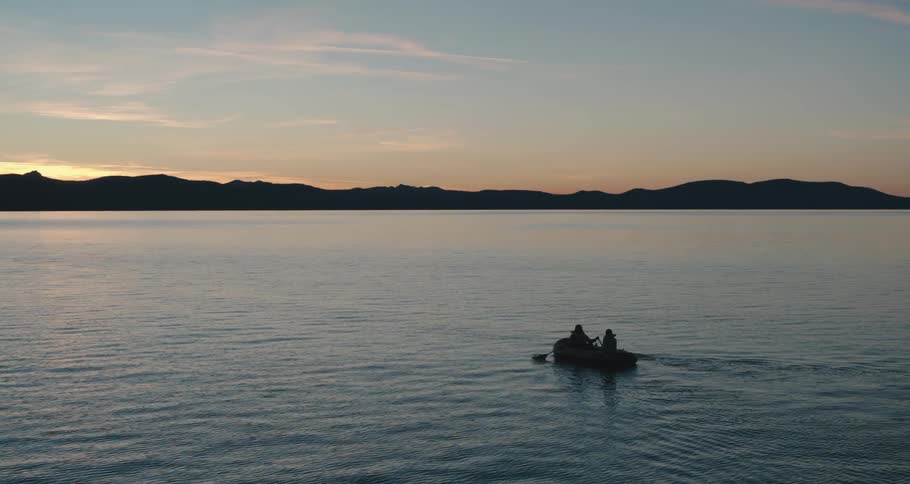An aerial view of a rowboat on a lake at dusk