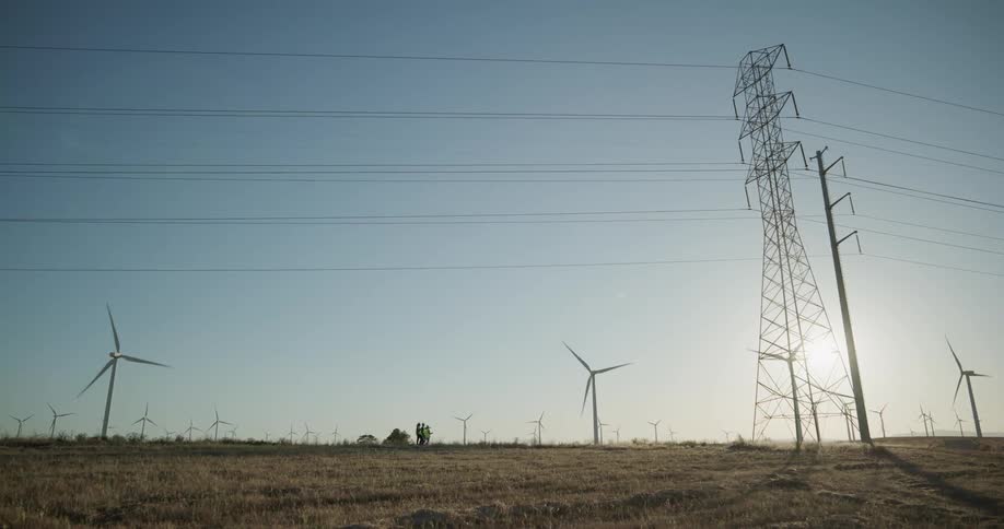 A windmill farm and electrical towers on a field